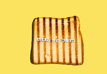 Top view piece of bread toasted in toaster with inscription acrylamide. Concept of  formation of...