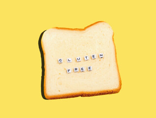 Top view slice of bread and word cubes with inscription gluten free. Gluten free bread concept on yellow background.