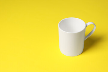 One white ceramic mug on yellow background, space for text