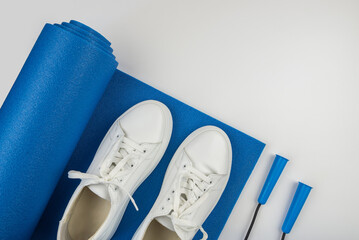 The concept of sports accessories. Photo of white sneakers, blue dumbbells