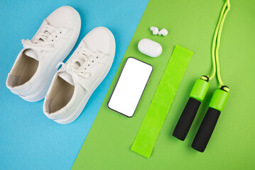 The concept of sports accessories. Photo of blue dumbbells and a blue exercise mat, white sneakers and other sports equipment.