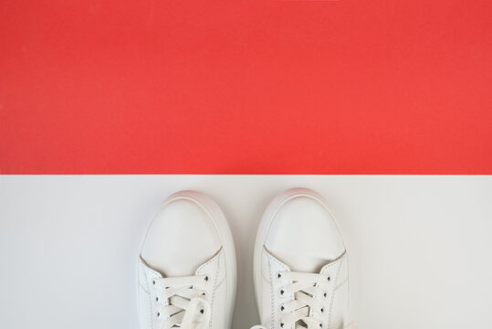Top view photo of white sneakers on red background