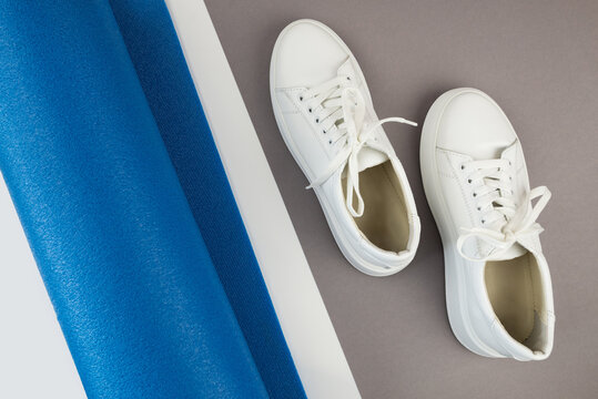 Top view photo of white sneakers and fitness mat.