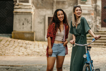 Two females posing for a shoot with a male photographer on a sunny day in the city.