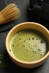 Cup of fresh matcha tea on black table, closeup