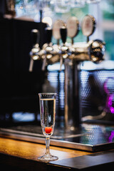 Glass of champagne on counter.
Cocktail cherry in prosecco.