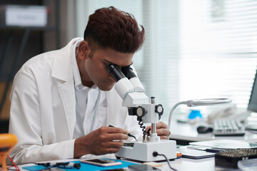 Engineer looking through microscope when repairing hard drive