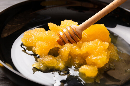Crystallized honey and wooden dipper in a plate close-up