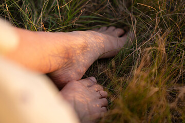 The bare feet of a young woman are buried in the grass