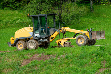Motor grader levels the ground on the gravel road 