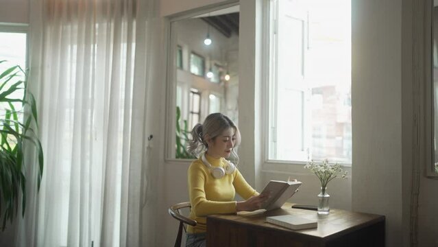 Beautiful young asian woman reading book at home Morning lifestyle concept.