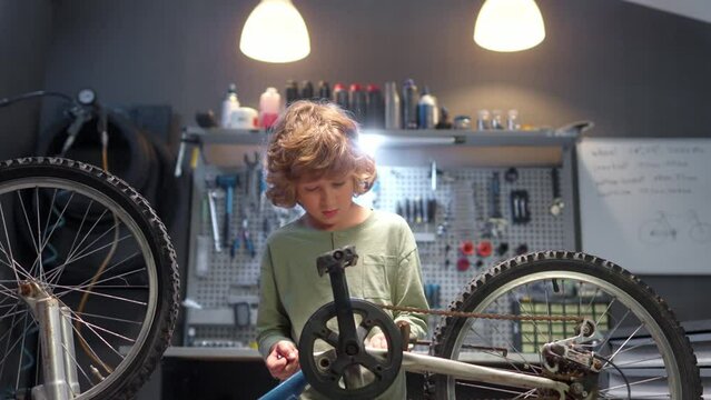 Little boy fixing bicycle chain at garage. Child repairing bike part at workshop. Male kid repairing bicycle pedals with wrench. Boy helping father with cycling repair. Mechanic knowledge.