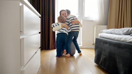Two little boy's running to loving mother at home. Concept of a happy childhood, playing indoors,...