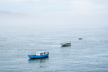 Fototapeta na wymiar Boats in river on misty morning with background with heavy fog. Lisbon, Portugal