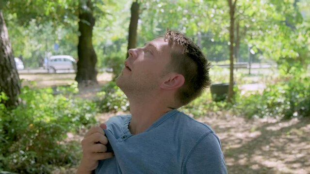 Man suffering from heat, guy with heatstroke. Caucasian male drinking water to cool off suffering from heat wave, stuffiness. Exhausted tired overheated man