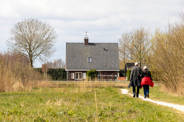 Abcoude, The Netherlands 4-1-2020: Elderly couple walks on a path in nature in the direction of a house