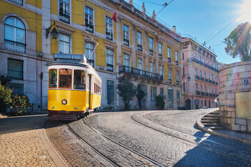 Famous vintage yellow tram 28 in the narrow streets of Alfama district in Lisbon, Portugal - symbol of Lisbon, famous popular travel destination and tourist attraction - 625312335
