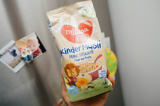 Paris, France - June, 3 2023: Milupa Kinder Musli in male hand with fridge with multiple magnets in background
