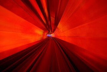 A frontal view from a subway driving in a red illuminated tunnel 