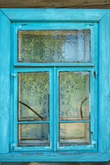 Wooden blue window shutters on the wall of an old dilapidated wooden house in the village. The destroyed abandoned dwelling after the cataclysm.