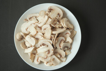 Fresh champignons mushroom in a white bowl on table 