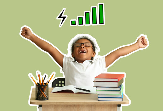 Happy little African-American girl sitting at desk against green background