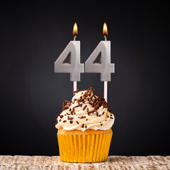 Birthday candle number 44 - Anniversary cupcake on black background