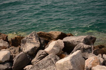 Fototapeta na wymiar Large stones on a wild beach near the blue sea