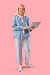 Mature female programmer working with laptop on pink background