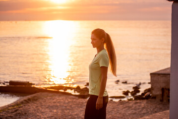 Portrait of young woman in sportswear, stopped for break between workouts. Sportswoman looks at dawn