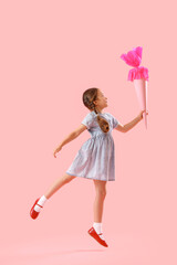Happy little girl with school cone jumping on pink background