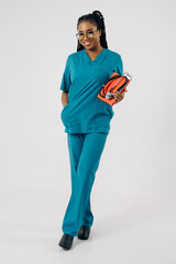 Portrait of smiling african american woman holding stethoscope  and book against white background, hospital, medical occupation concept