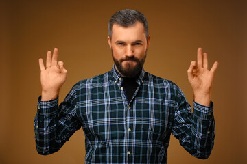 Handsome man with beard.Plaid shirt. Shows okay with two hands.