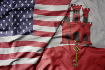 big waving colorful flag of united states of america and national flag of gibraltar .