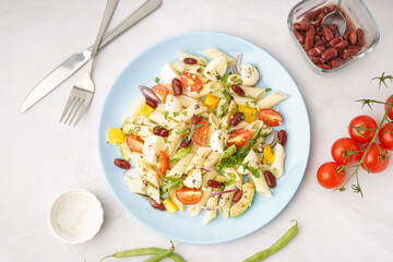 Plate of tasty pasta salad with tomatoes and beans on white background
