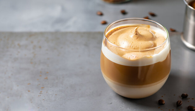 Dalgona frothy coffee in glass on grey. Trend korean drink latte with foam of instant coffee. Close up.