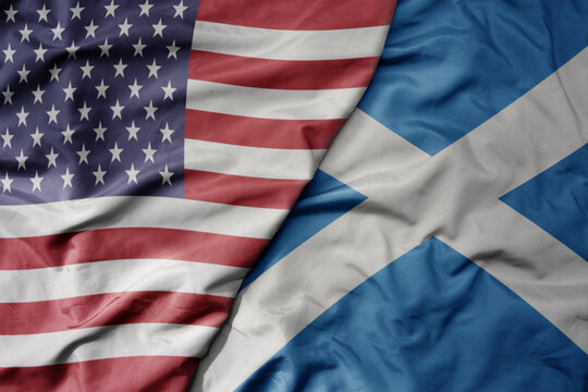 big waving colorful flag of united states of america and national flag of scotland .