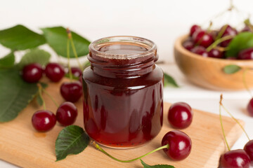 Jar with tasty homemade cherry jam on wooden table
