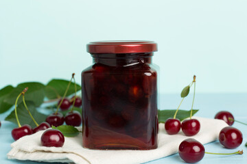 Jar with tasty homemade cherry jam on wooden table