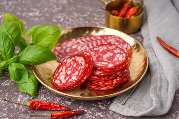 Plate with slices of tasty salami on grey background