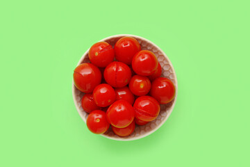 Bowl with canned tomatoes on green background
