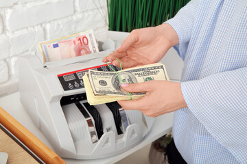 Woman counting money near cash register on shelf in office, closeup