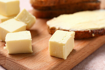 Pieces of fresh butter on wooden board, closeup