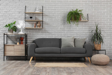 Interior of modern living room with sofa and electric fan on shelf