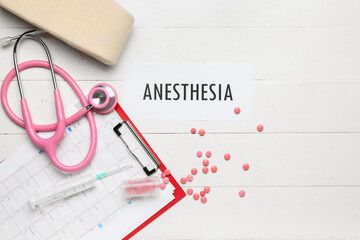 Paper with word ANESTHESIA, clipboard, stethoscope and pills on white wooden background
