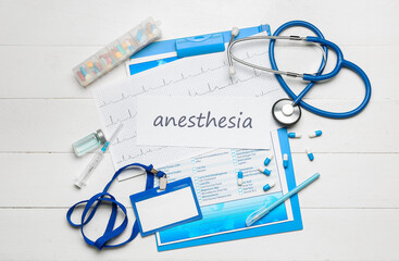 Clipboard with word ANESTHESIA and medical supplies on white wooden background