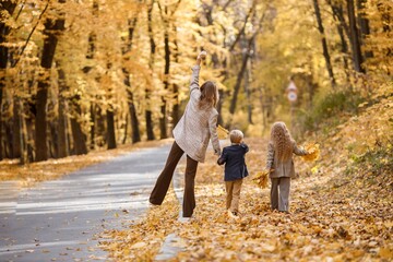 Mother and her children playing and having fun in autumn forest