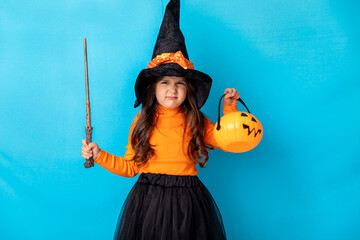 Halloween Party girl. Funny child girl in witch costume celebrates Halloween with magic wand and...