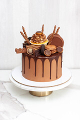 Chocolate cake richly decorated with assorted sweets, cupcake, cookies, chocolate bars and macarons