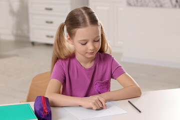 Naklejka premium Girl using eraser at white desk in room